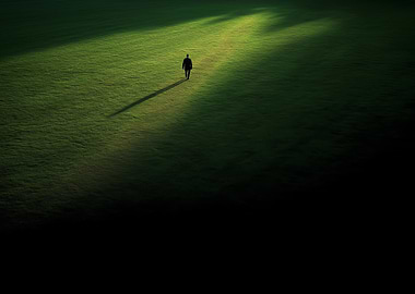 Lone figure walking in green field