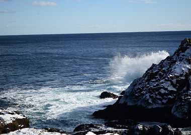 Ocean waves crashing on snowy rocks