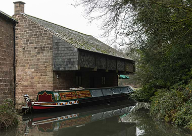 Canal boat docked by stone building
