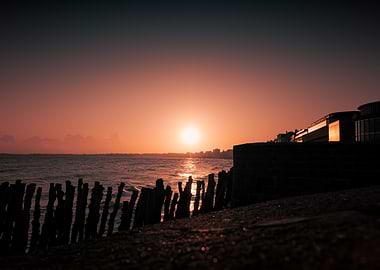 Sunset over the ocean with wooden posts