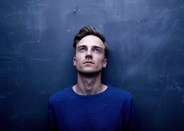 kenay spanish musician looking up against blue wall