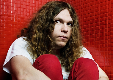 jay reatard with long curly hair in red corner