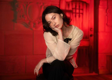 Gracie Abrams in sheer blouse with black bow