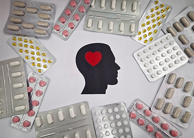 Pills surrounding a silhouette of a head with a heart
