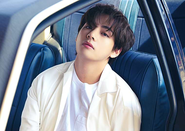 V in white jacket in car