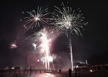 Fireworks display over a pier at night