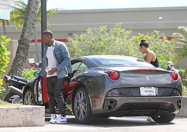 Man with drinks by a Ferrari