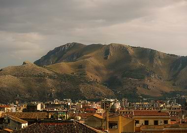Cityscape with Mountains Under Cloudy Sky