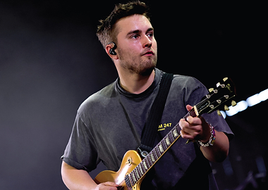 Musician playing guitar on stage Sam Fender