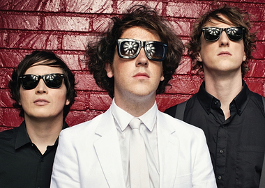 Three men in sunglasses and suits The Wombats