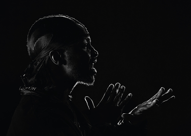 jme in silhouette speaking with hands raised