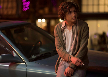 Young man leaning on a car at night