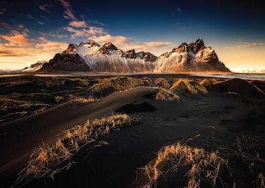 Snow-capped mountains over black sand dunes