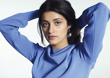 Anya Chalotra in blue sweater with hands behind head