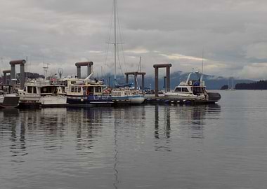 Boats docked in Juneau, Alaska harbor under cloudy skies