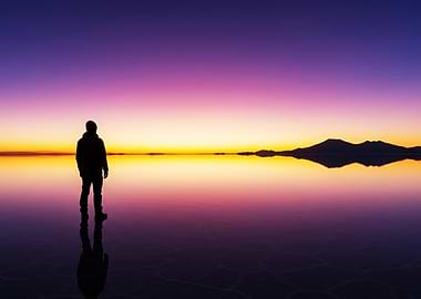 Man silhouetted against a vibrant sunset reflection