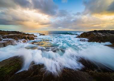 Waves crashing on rocky shore at sunset