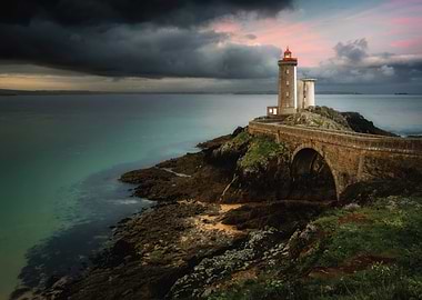 Lighthouse on a rocky island at sunset
