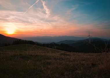 Sunset over rolling hills with wind turbines