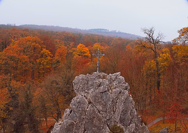 Cross on a rocky outcrop in autumn forest