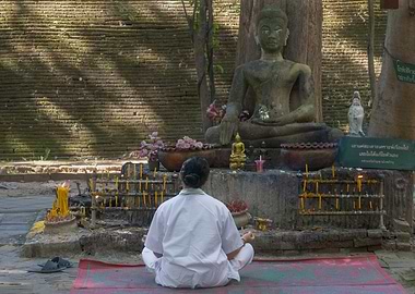 Woman Meditating Before Buddha Statue